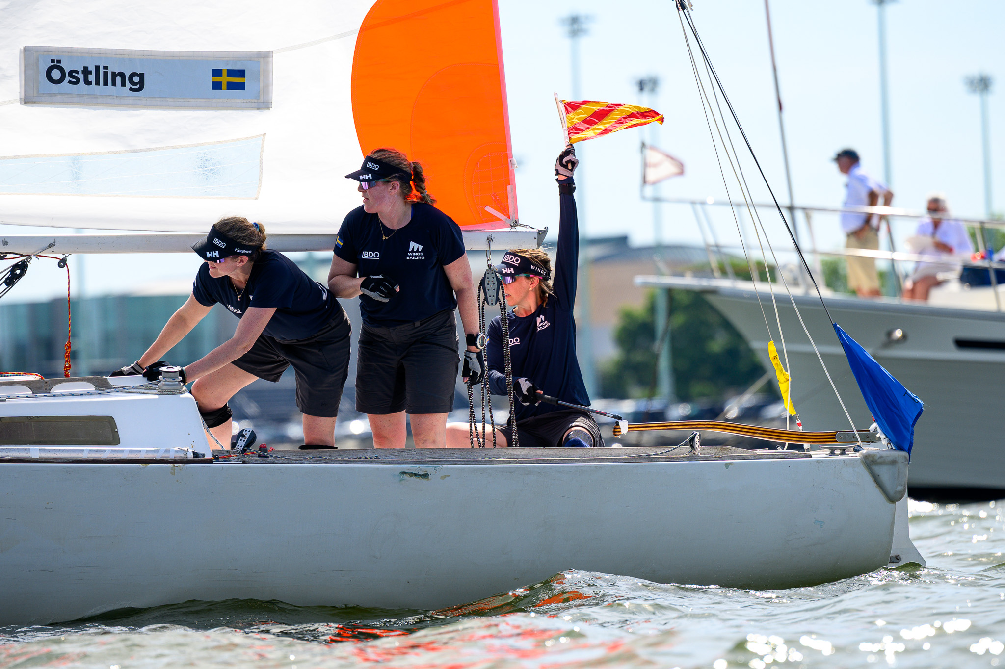 Sailor celebrating with arm raised under an orange spinnaker